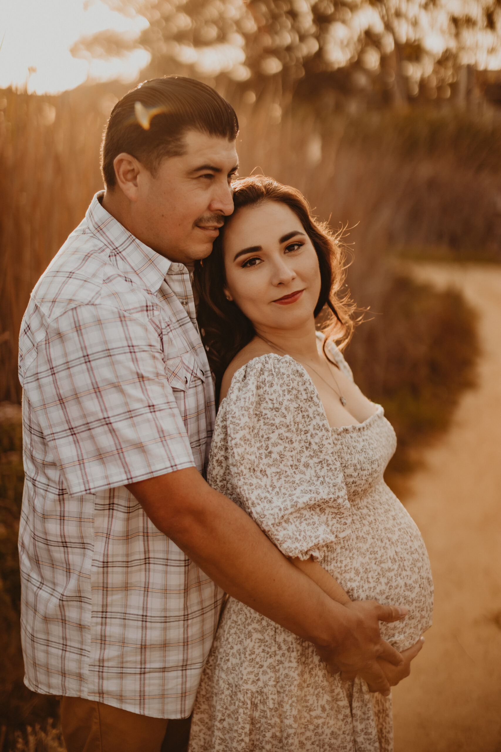 Pregnant woman and man cuddling during a maternity shoot at a lagoon in San Diego
