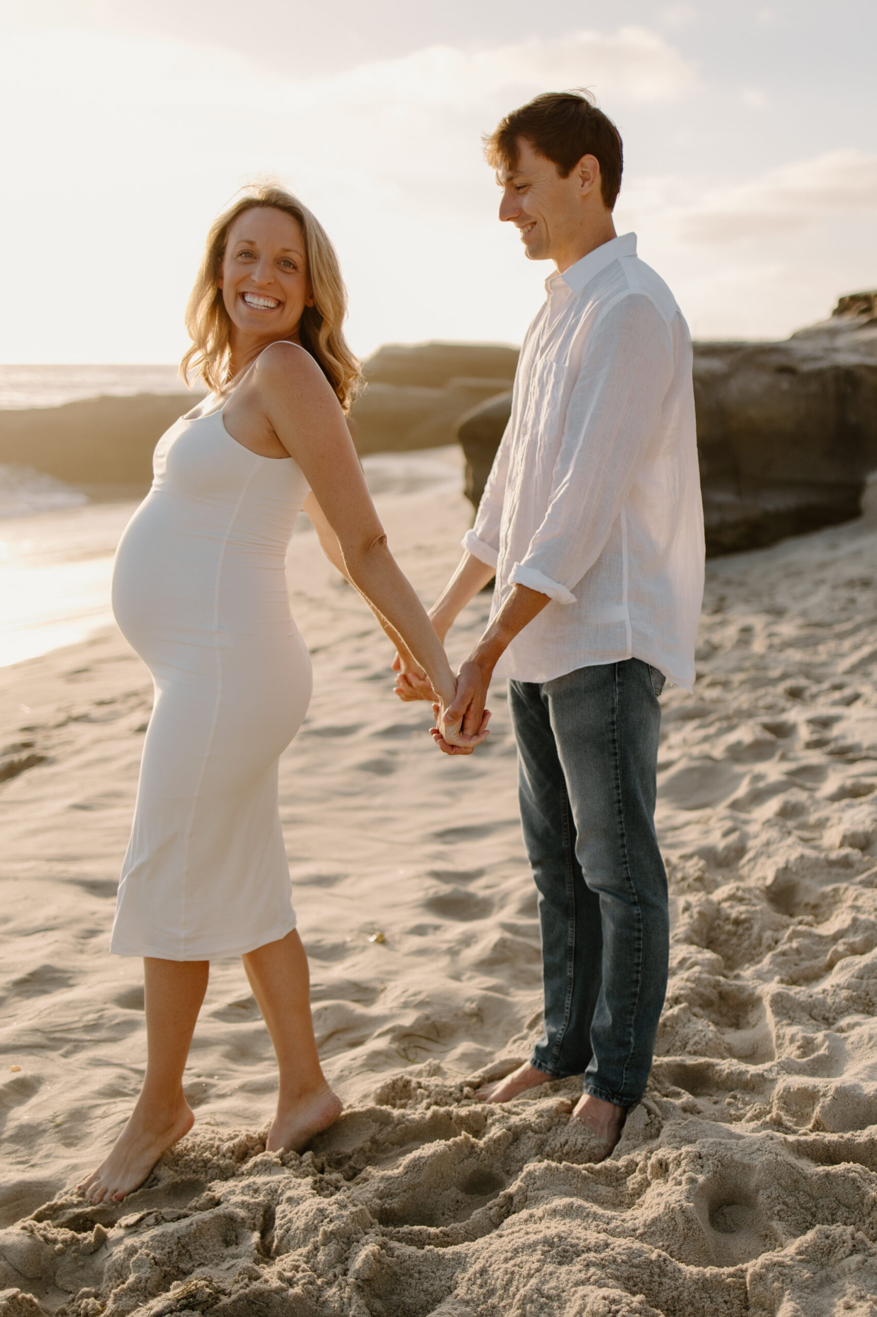 Pregnant woman and man standing on a beach in san diego during their maternity session